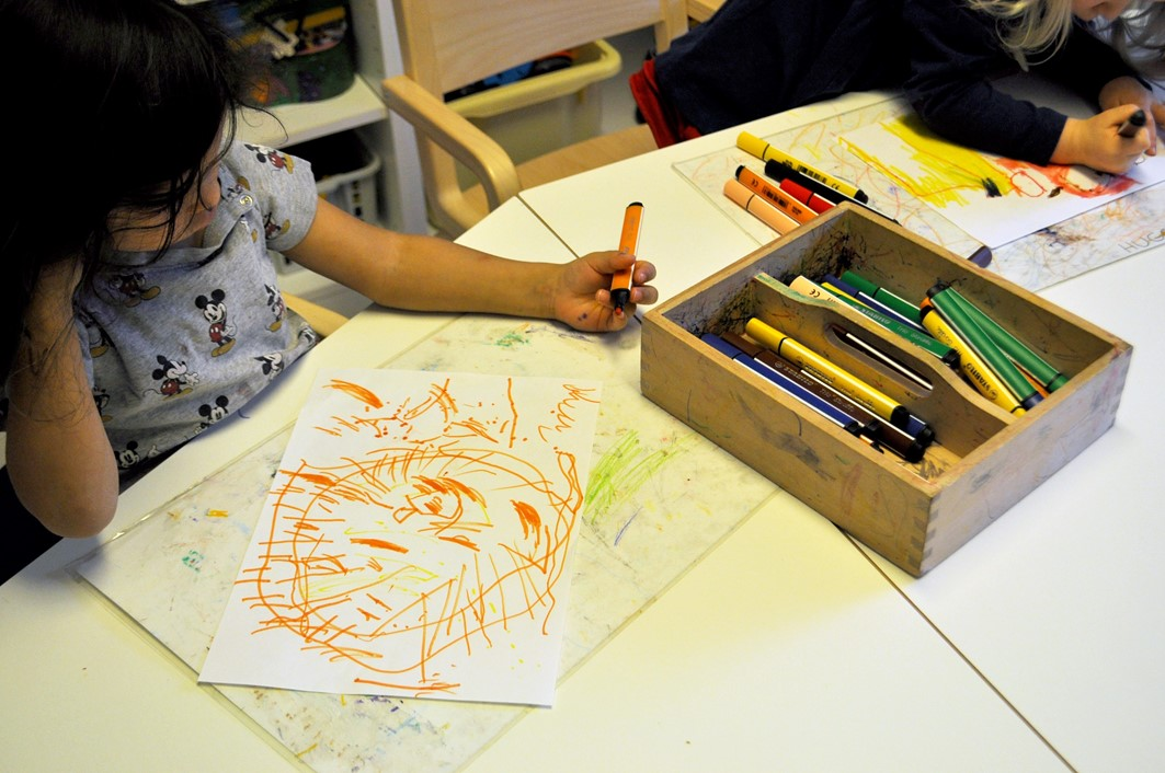 Lapsi ja lapsen piirtämä piirros.