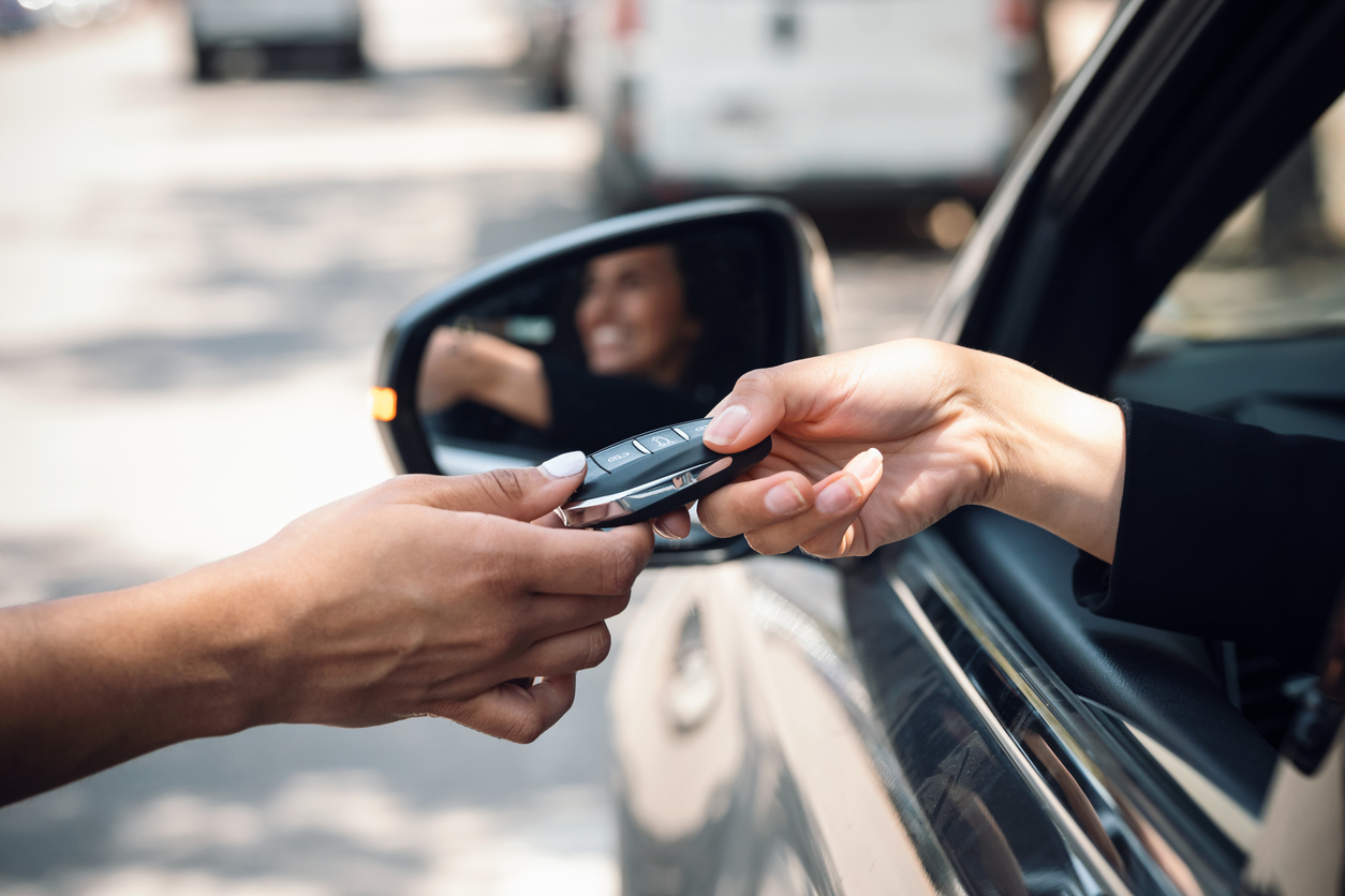 A woman hands overs rental car keys to a driver.