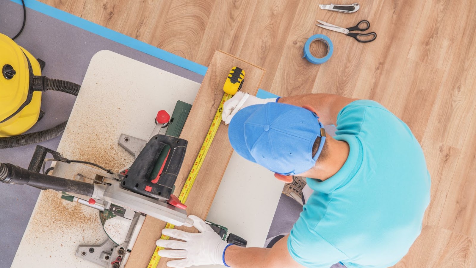 A contractor busy cutting a laminate floor board.