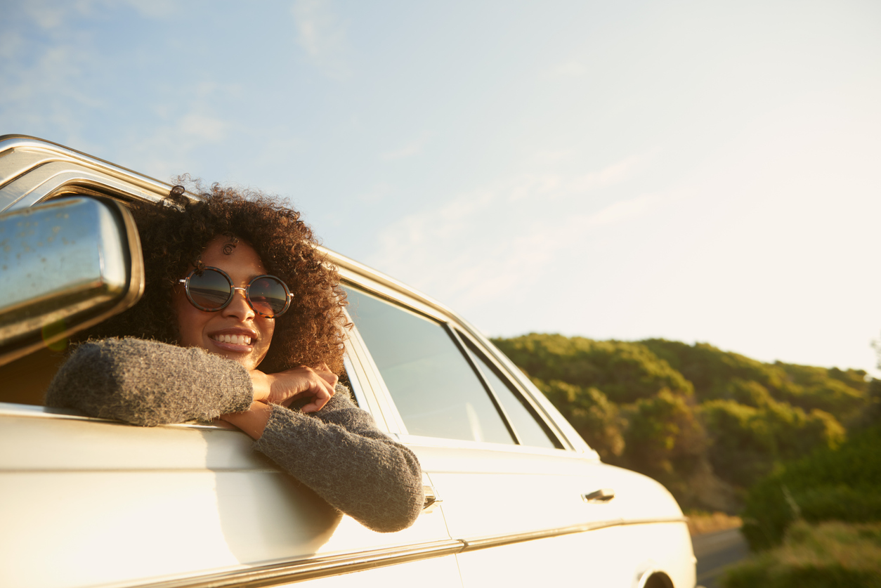 A young renter looking outside of her renter car window.