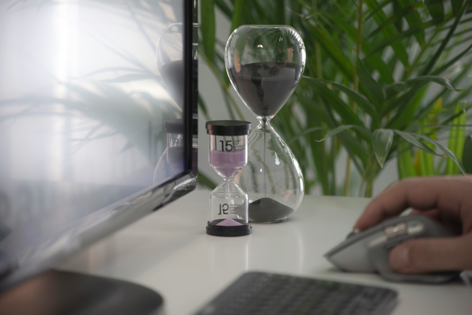 Person working on computer with two hourglasses on the desk